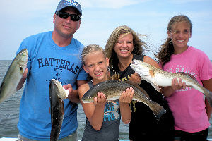 Family visiting Hatteras holding their inshore charter catch.