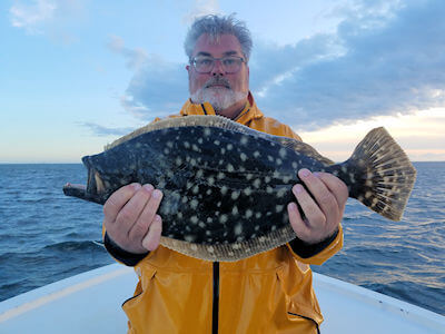 Angler holding large flounder.