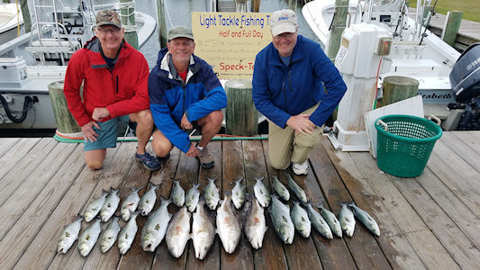 Two anglers standing behind a nice catch laid out on the docks at Teach's Lair Marina.